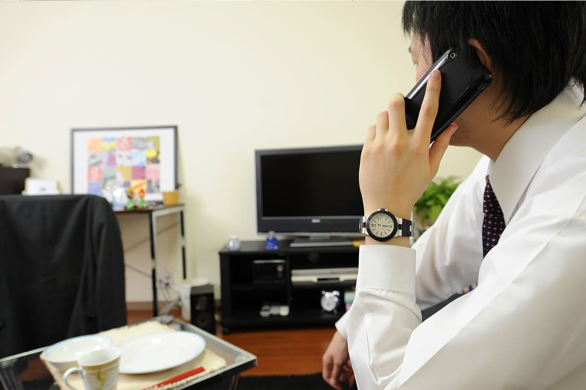 部屋で電話をする男性